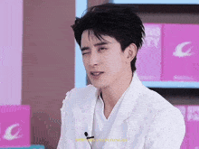 a man in a white jacket is sitting in front of a sign that says ' g '