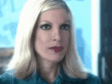 a close up of a woman 's face with blonde hair and red lips .
