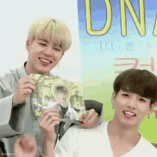 two young men are standing next to each other in front of a sign that says dn