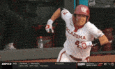 a baseball player wearing an oklahoma jersey runs towards home plate