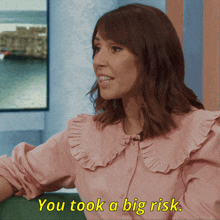 a woman in a pink ruffled blouse says you took a big risk