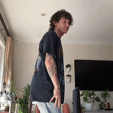 a man in a black shirt with a tattoo on his arm is standing in front of a television