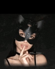 a woman wearing a cat mask is holding her finger to her lips