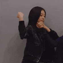 a woman in a black leather jacket is flexing her arm