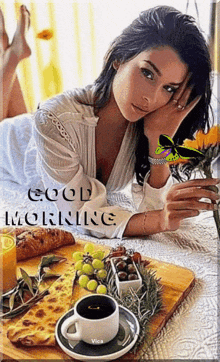 a woman is laying on a bed with a cup of coffee and a tray of food