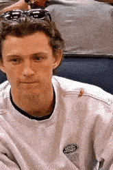 a close up of a man wearing sunglasses and a white sweatshirt .