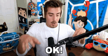 a man in a white shirt is sitting in front of a microphone and says ok .