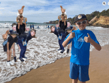 a boy wearing a blue shirt with the letter a on it is giving a thumbs up