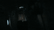 a dark room with boxes on the floor and a man in a blue jacket