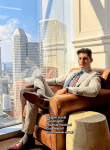 a man in a suit sits in a chair in front of a window and says goodnight
