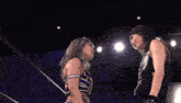 two women are wrestling in a dark room and one is wearing a black tank top