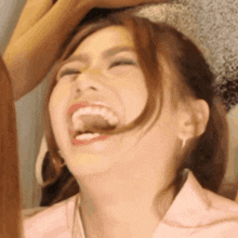 a woman is laughing with her eyes closed and her mouth open .