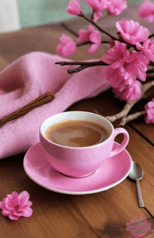 a cup of coffee on a saucer next to pink flowers and chopsticks