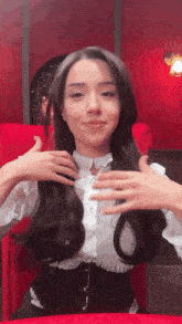 a woman is sitting in a red chair and holding her hair