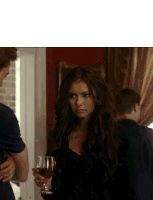a woman holding a glass of wine stands next to a man in a room