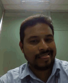 a man with a beard wearing a blue shirt with a lanyard that says ' nokia ' on it