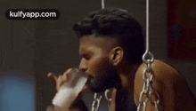 a man is drinking milk from a bottle while chained to a pole .