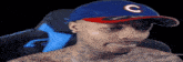 a shirtless man wearing a blue and red baseball cap with the letter c on it .