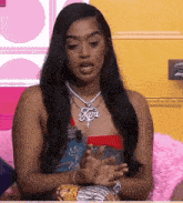a woman wearing a tara necklace sits on a couch