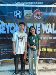 a man and a woman standing in front of a banner that says beyond the wall