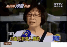 a woman wearing glasses is talking into a microphone on a tv channel