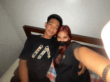 a man and a woman are posing for a picture and the man is wearing a shirt that says a on it