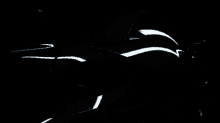 a car is parked in a dark room with a white light shining on it 's tail light