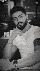a man with a beard is wearing a watch with the letter m on it