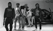a group of young men are standing in front of a car .