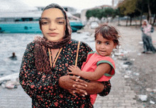 a woman in a floral dress holds a little girl in her arms
