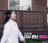 a woman walking in front of a wooden house with chinese writing on the side