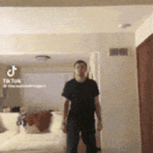 a man in a black shirt is standing in a living room with a couch .