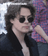 a man wearing sunglasses and a plaid shirt has the words paris videostars above him