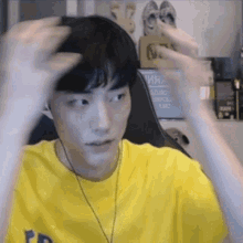 a young man wearing a yellow t-shirt and headphones is playing a video game in a room .