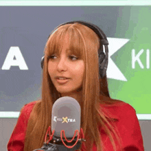 a woman wearing headphones and a red jacket is talking into a microphone .