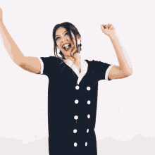a woman in a black and white dress is raising her arms in the air