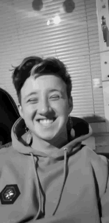 a black and white photo of a person wearing a hoodie smiling .