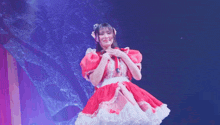 a girl in a red dress is making a heart with her hands on a stage