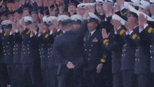 a group of military men are standing in a line applauding
