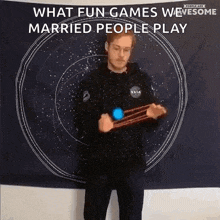 a man is playing a game in front of a tapestry that says `` what fun games we married people play '' .