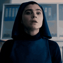 a woman wearing a blue head scarf and a blue apron looks surprised
