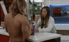 a man without a shirt is sitting at a table with a woman eating .