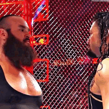 a man with a beard is standing next to another man with a beard in front of a chain link fence .