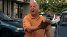 a man in an orange shirt is holding a glove in front of a store that says ' devil '