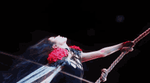 a woman in a black dress is holding a rope