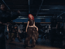 a woman with red hair is dancing in a dark room with a sign on the wall that says ' a ' on it