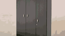 a black wardrobe with three doors and a key in the lock