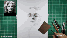 a drawing of marilyn monroe sits on a green cutting mat