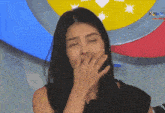 a woman covering her mouth with her hand in front of a sign that says ' kara '
