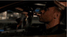 a man is drinking from a bottle while driving a car .